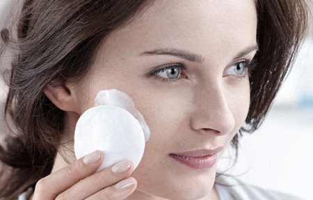 Žena nanosi kremu na lice blazinicom